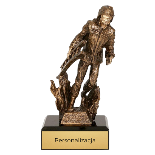 Statuetka odlewana RTYR3768 Strażak w Pożarze w kolorze brązu na ciemnej podstawie. Model przedstawia strażaka wśród płomieni i sprawdzi się jako nagroda, wyróżnienie lub podziękowanie dla strażaków. Miejsce na tabliczkę z nadrukiem.